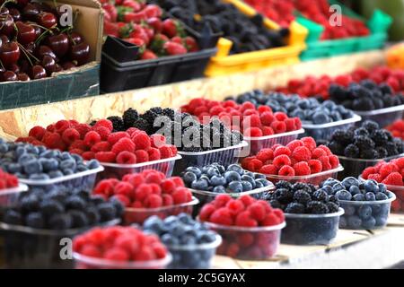 Himbeeren, Heidelbeeren und Brombeeren auf dem Markt in Plastikschalen. Obst-Muster. Stockfoto