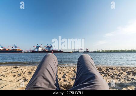 Entspannen am Elbstrand in Hamburg mit Hafen und Schiffen im Hintergrund Stockfoto