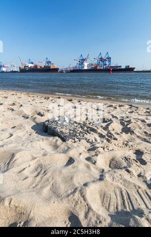 Strand an der Elbe in Hamburg mit Containerterminal und Schiffen im Hintergrund Stockfoto