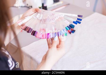 Junge Frau Hände Wahl Nagellack. Weibliche Hand und Nagelfarbe Proben, Schönheitssalon. Stockfoto