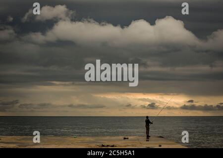 3. Juli 2020, Barcelona, Katalonien, Spanien - Ibrahim wirft seine Angelrute vom Pier von La Barceloneta, während die Sonne nach einer stürmischen Nacht in Barcelona aufgeht. Quelle:Jordi Boixareu/Alamy Live News Stockfoto