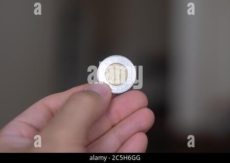 Personen Hand hält eine Toonie oder zwei Dollar-Münze, die Währung des Kanada - auf einem braunen Hintergrund. Geldwechsel. Stockfoto