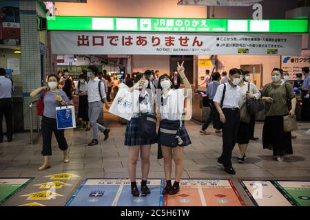 Tokio, Japan. Juli 2020. Japanische High School Studenten nehmen Selfies während der Rush-Hour an Shinagawa StationDie japanische Regierung hat den Bewohnern geraten, überfüllte Plätze am Abend aufgrund der steigenden Anzahl von Coronavirus Covid-19 Infektionen nach der Wiedereröffnung der Wirtschaft zu vermeiden. Kredit: SOPA Images Limited/Alamy Live Nachrichten Stockfoto