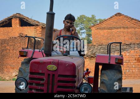 TIKAMGARH, MADHYA PRADESH, INDIEN - 15. NOVEMBER 2019: Indischer Dorfjunge lächelt durch ein Gespräch auf einem Handy. Stockfoto