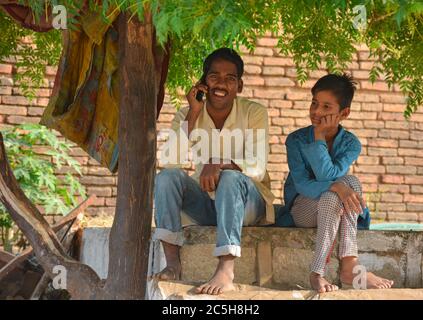 TIKAMGARH, MADHYA PRADESH, INDIEN - 15. NOVEMBER 2019: Indischer Dorfjunge lächelt durch ein Gespräch auf einem Handy. Stockfoto