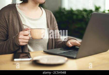 Freelace Geschäftsfrau Hand hält Kaffee Tasse Arbeit mit Laptop Stockfoto