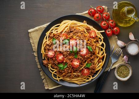 Pasta Bolognese bucatini mit Hackfleisch und Tomaten, dunkler Holzhintergrund, Draufsicht, Kopierraum Stockfoto