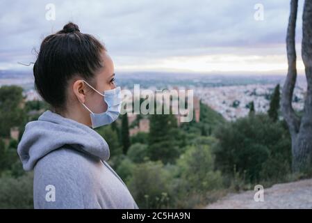 Die Nahaufnahme einer Frau mit Maske. Gefährliche Infektionskrankheiten. Junges Mädchen mit Maske in der Stadt mit der Alhambra im Hintergrund. Stockfoto