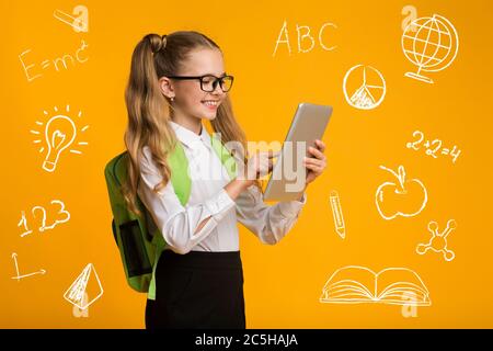 Bildung und Gadgets. Nettes Schulmädchen in Brille mit Tablet, um Symbole der Bildung Stockfoto