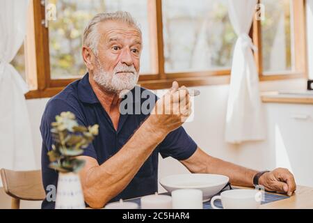 Elder Essen Gesichtsausdruck Fühlen Sie sich überraschen mit sehr guten Geschmack von Essen von seiner Frau Stockfoto