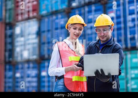 Logistikarbeiter Mann und Frau Arbeitsteam mit Online-Wireless-Laptop-Steuerung Laden Container im Hafen Fracht auf LKW für den Export und Import von Waren Stockfoto