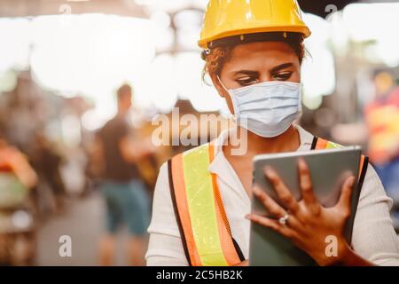 Afroamerikanische schwarze Frauen Teen Arbeiter tragen Gesichtsschutz oder Einweg-Gesichtsmaske während der Arbeit in der Fabrik für die Ausbreitung von Coronavirus verhindern (Co Stockfoto