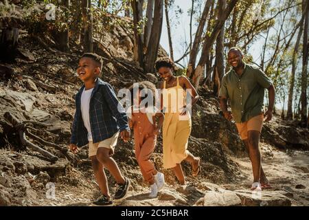 Junge Familie genießt ihren Urlaub in einem Nationalpark. Afrikanische Familie, die einen Bergweg hinunter geht und Spaß hat. Stockfoto