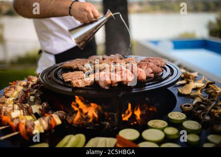 Der Koch grillt Fleisch und Gemüse im Hinterhof Stockfoto