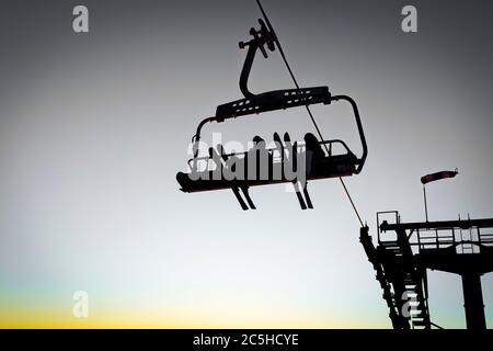 Silhouetten von Skifahrern auf Sesselliften am Abend, Sonnenuntergang Licht Stockfoto