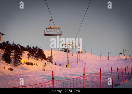 Silhouetten von Skifahrern auf Sesselliften am Abend, Sonnenuntergang Lichter Stockfoto