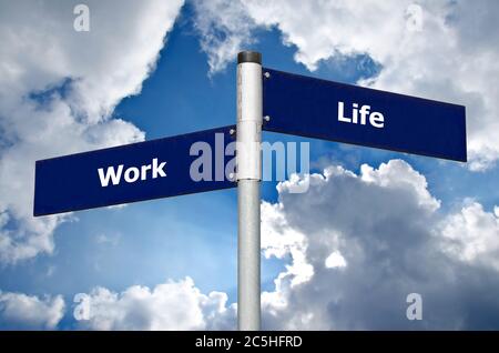 Straßenschild vor dem wolkigen Himmel symbolisiert die Wahl zwischen Arbeit und Leben Stockfoto