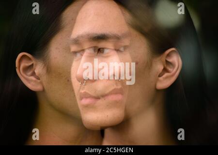 Junger asiatischer Mann mit langen Haaren in der Stadt mit mehrfacher Belichtung Stockfoto