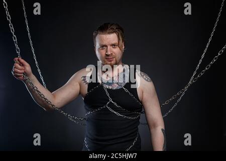Foto eines tätowierten Mannes, der in Ketten gebunden ist Stockfoto