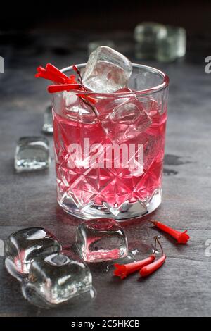 Kosmopolitischer Cocktail in einem Glas mit rosa Blumen close up auf grauen Tisch dekoriert Stockfoto