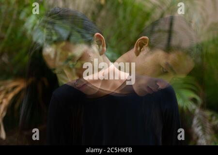 Junger asiatischer Mann mit langen Haaren im Park mit mehrfacher Belichtung Stockfoto