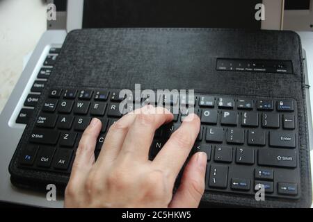 Nahaufnahme der Schreibarbeit auf der Laptop-Tastatur von jungen Mann Hände. Business-Handel Copywriting Konzept Stockfoto