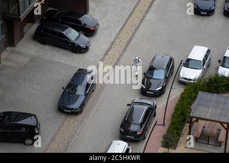 UKRAINE, KIEW - 20. Mai 2020: Der Mann in einem weißen Schutzanzug und einer Maske geht auf einer Straße, um Innenflächen in Gebäuden zu sanieren Stockfoto