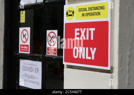 Soziale Distanzierung im Betrieb ein Meter Ausgang nur Schild mit Praxis soziale Distanzierung Zeichen im Hintergrund auf Pub Tür. Neue Richtlinien ab 4. Juli. Stockfoto