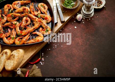 Gegrillte Garnelen in gusseiserner Grillpfanne mit frischer Zitrone, Petersilie, Chili, Knoblauch Weißweinsauce Stockfoto