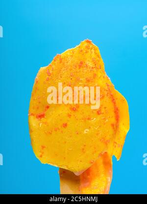 Orangengeschmack Popsicle in einem Schmelzprozess auf einem blauen Hintergrund Stockfoto