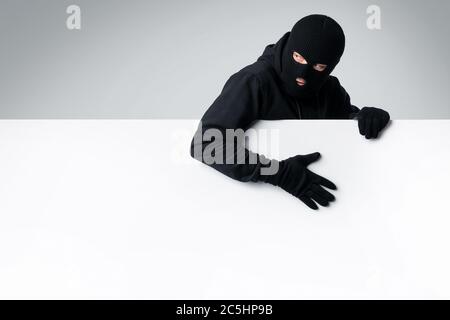 Maskierter Dieb mit weißen leeren Werbetafel Stockfoto