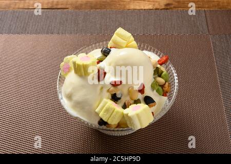 Seitenansicht Schüssel mit Vanille Geschmack Eiscreme Kugeln mit Marshmallows und verschiedenen Nüssen in einem Schmelzprozess Stockfoto