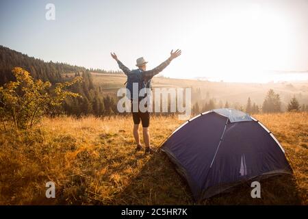 Glücklicher Wanderer treffen Sonnenuntergang auf dem Gipfel des Berges. Touristen bewundern Sie die inspirierende Landschaft mit den Händen hoch. Der Kletterer erreichte den Berggipfel Stockfoto