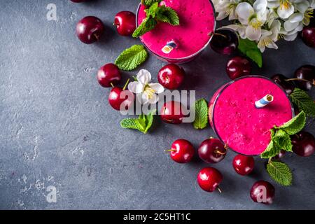 Süßer Kirsch-Smoothie-Drink in Gläsern mit Minzblättern und frischen Beeren Stockfoto