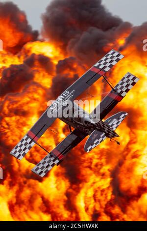 Kunstflugpilot Skip Stewart fliegt mit seinem hochmodifizierten Pitts S-2S Doppeldecker Prometheus vor die spektakuläre Feuerpyrotechnik-Wand. Stockfoto