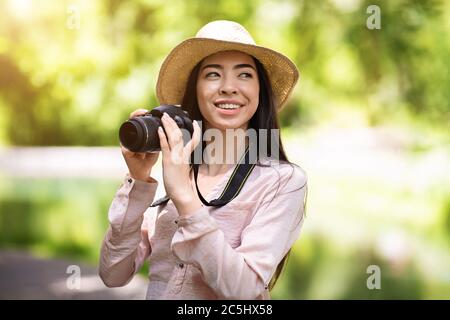 Hobbies Im Freien. Glücklich asiatische Frau Reisende Foto mit modernen Kamera Stockfoto