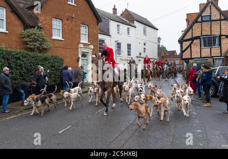 WINSLOW, Großbritannien - 26. Dezember 2018. Fuchsjagd, Männer in Kostümen reiten auf Pferden mit einem Rudel von Jagdhunden durch eine ländliche Stadt in Buckinghamshire, England Stockfoto