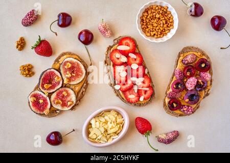 Gesunde Frühstückstösti mit Erdnussbutter, Erdbeere, Maulbeere, Kirsche und Feige. Draufsicht Stockfoto