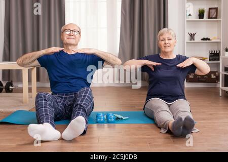 Ältere Menschen, die einen gesunden Lebensstil haben, Sport im Wohnzimmer zu treiben. Alter gesunder Lebensstil Bewegung zu Hause, Training und Training, sportliche Aktivität zu Hause auf Yoga-Matte. Stockfoto