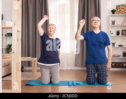 Ältere Paare treiben gerne gemeinsam Sport zu Hause. Alter gesunder Lebensstil Bewegung zu Hause, Training und Training, sportliche Aktivität zu Hause auf Yoga-Matte. Stockfoto