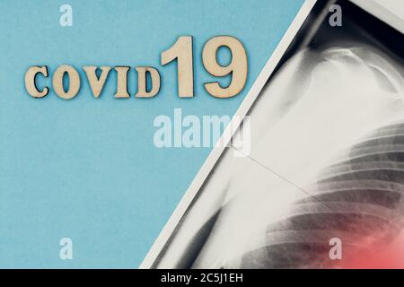 Coronavirus, covid-19. Die Inschrift covid-19 und Röntgenaufnahme der Lunge auf blauem Hintergrund. Selbstisolation und Quarantäne, Lungenentzündung Stockfoto