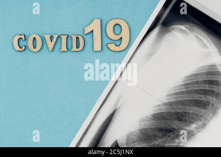 Coronavirus, covid-19. Die Inschrift covid-19 und Röntgenaufnahme der Lunge auf blauem Hintergrund. Selbstisolation und Quarantäne, Lungenentzündung Stockfoto