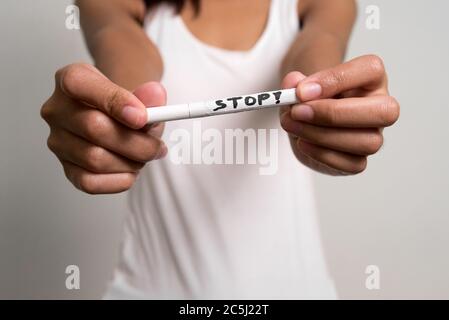 Junge asiatische Teenager-Mädchen hält Zigarette mit STOP-Zeichen Stockfoto