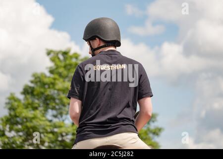 Junger männlicher Reiter mit Standard-Ausgabe Helm Reiten sein Pferd während eines sonnigen Tages gesehen. Stockfoto