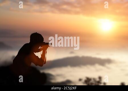 Silhouette des Fotografen, der Bilder von einem Sonnenuntergang in den Bergen. Stockfoto