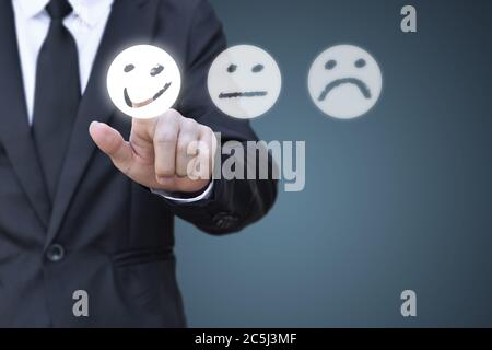 Geschäftsmann drücken Smiley Gesicht Symbol auf virtuellen Bildschirm. Konzept der Zufriedenheitsbewertung und Feedback. Stockfoto