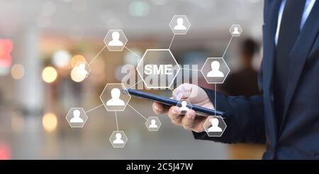 Mann Hand hält Smartphone mit Symbol Menschen auf dem virtuellen Bildschirm. Idee für KMU oder kleine und mittlere Unternehmen. Stockfoto