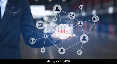Businessman shows outstretched hand with SME icon on virtual screen. Idea for Small and medium-sized enterprises business. Stockfoto