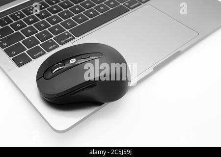 Isolierte Ansicht einer drahtlosen Bluetooth-Maus, die auf einem bekannten Notebook der Premiumklasse sitzt. Stockfoto