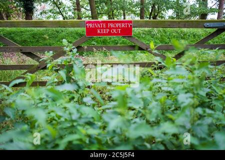 Isolierte Ansicht eines neu installierten Private Property Schild gesehen, die an einem Holz gebaut Wiese Tor. Überwuchert Nesseln können vor gesehen werden. Stockfoto